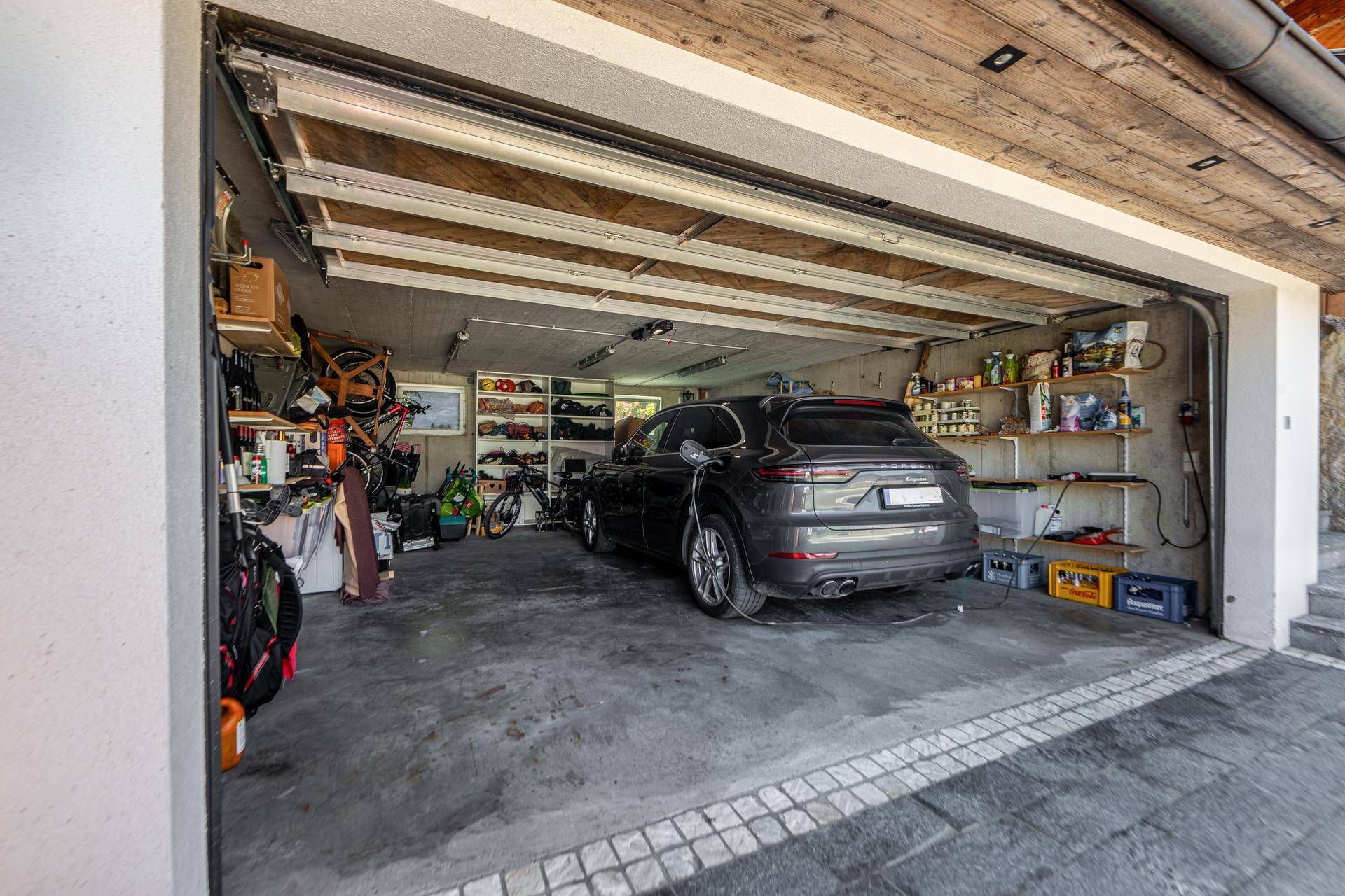 Geräumige Garage mit einem geparkten Auto, Stauraum und EV-Ladestation.