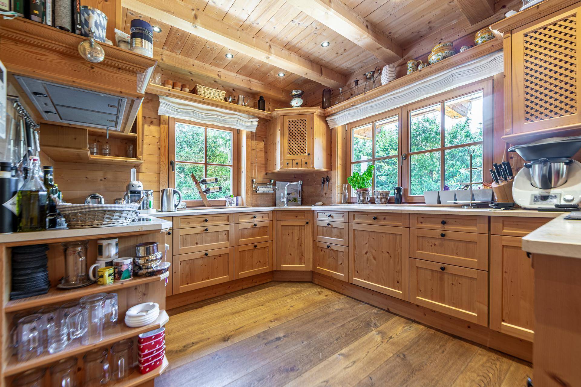 Helle Holzküche im Landhausstil mit viel Stauraum und Blick ins Grüne durch die Fenster.