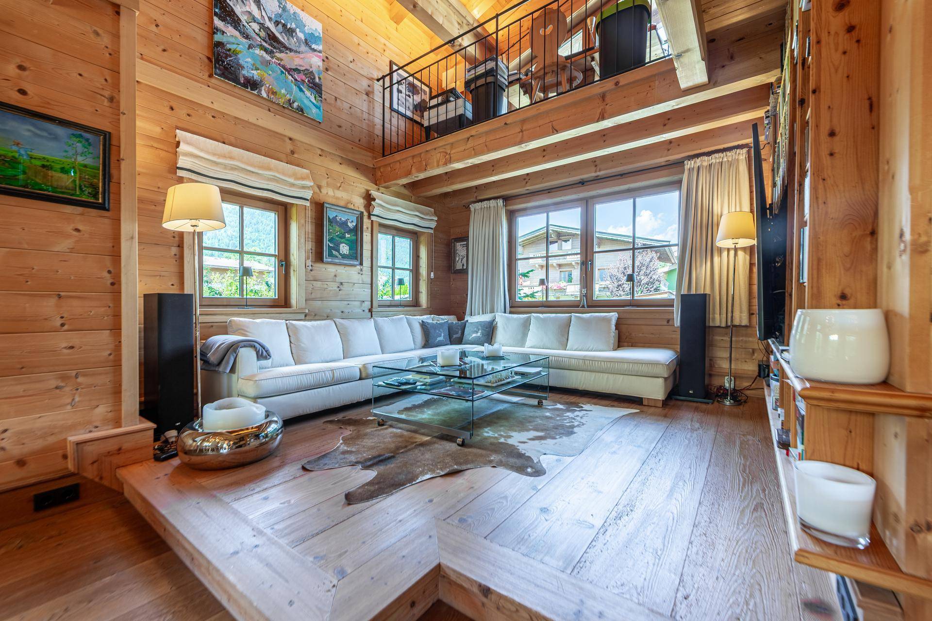 Großzügiges Wohnzimmer im Chalet-Stil mit hohen Holzdecken, bequemer Couch und Galerie.