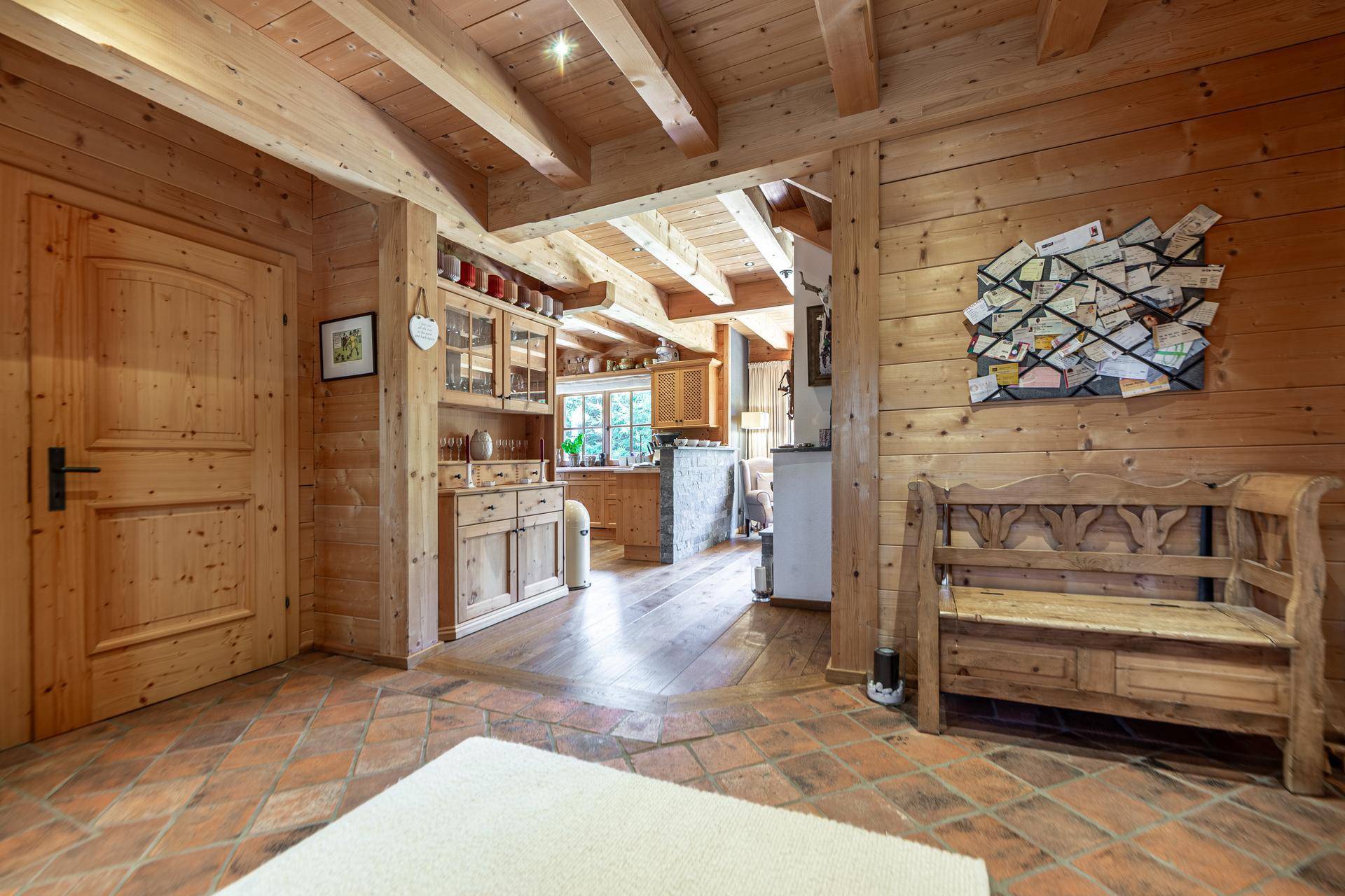 Geräumiger Flur mit Terrakotta-Boden, Holzvertäfelung und Blick in den offenen Wohnbereich.