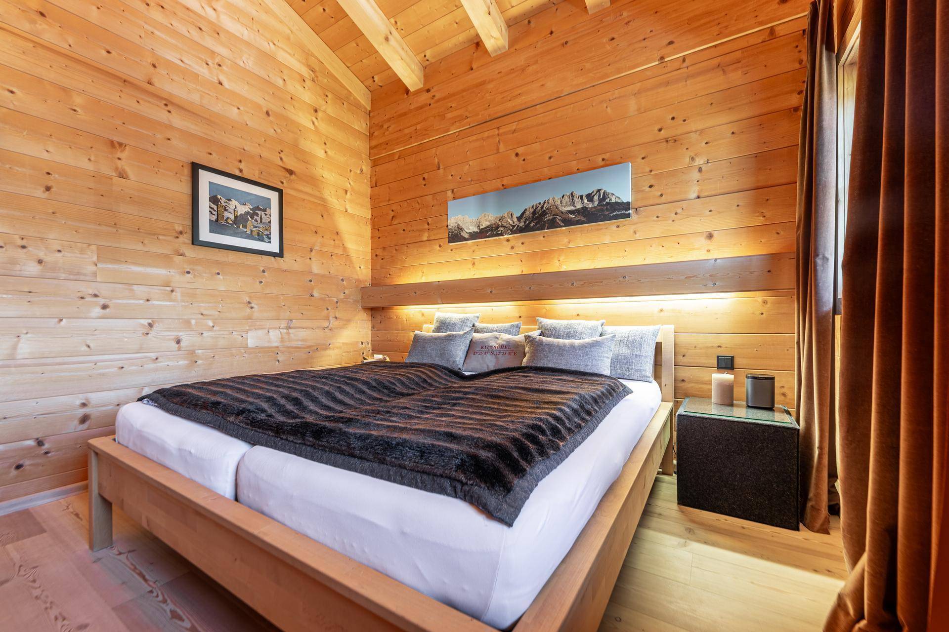 Gemütliches Schlafzimmer mit Holzwänden, Holzboden und einem großen Doppelbett mit Bergblick.