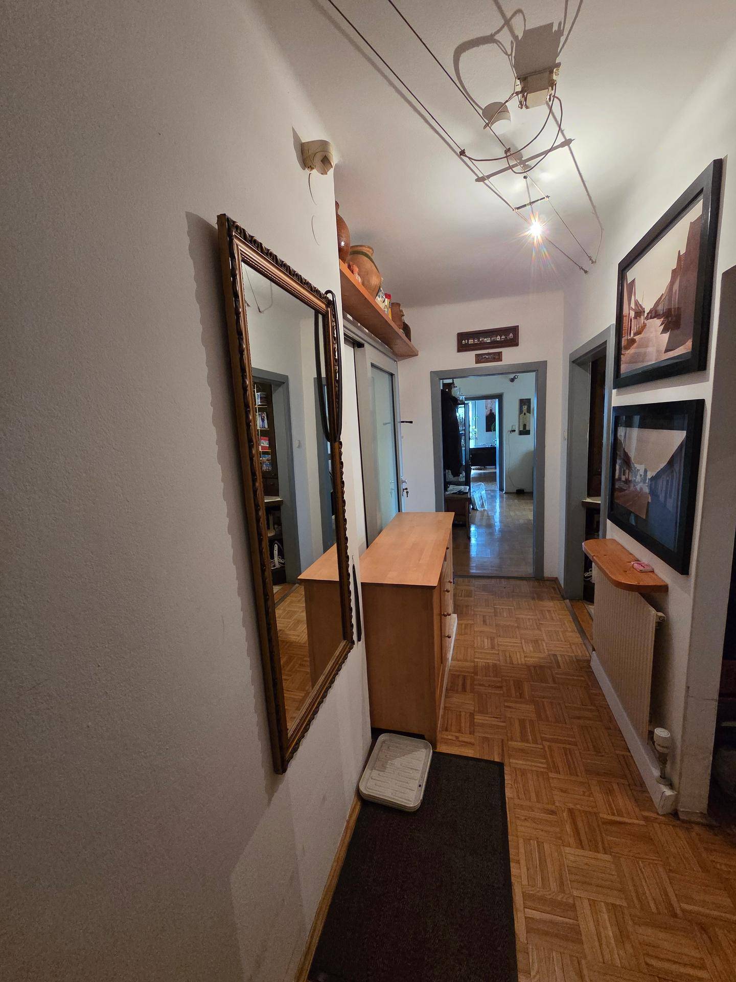 Heller Flur mit Parkettboden, großem Spiegel und Zugang zu weiteren Räumen.