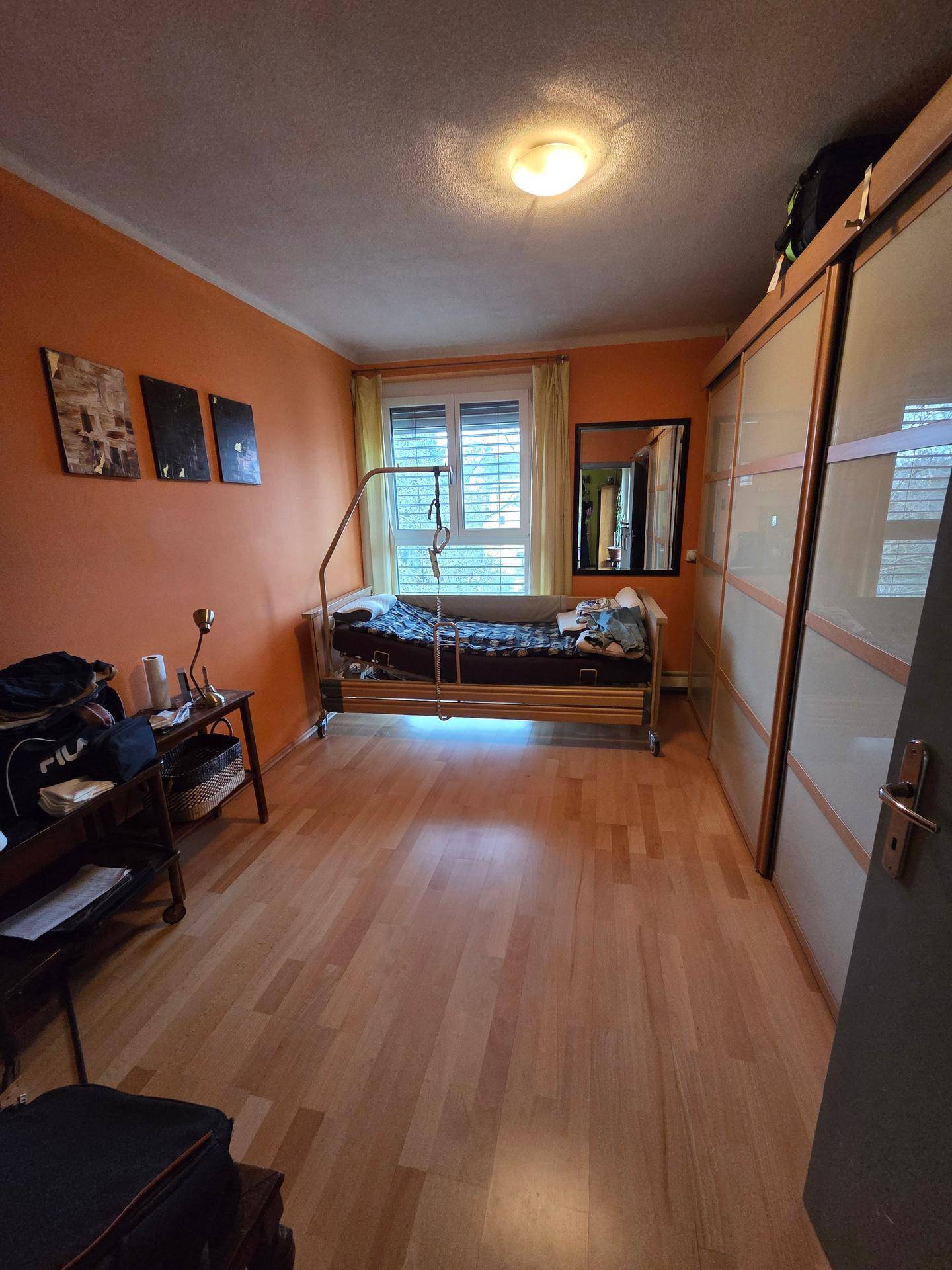 Schlafzimmer mit orangefarbenen Wänden, Holzfußboden und großem Einbauschrank.
