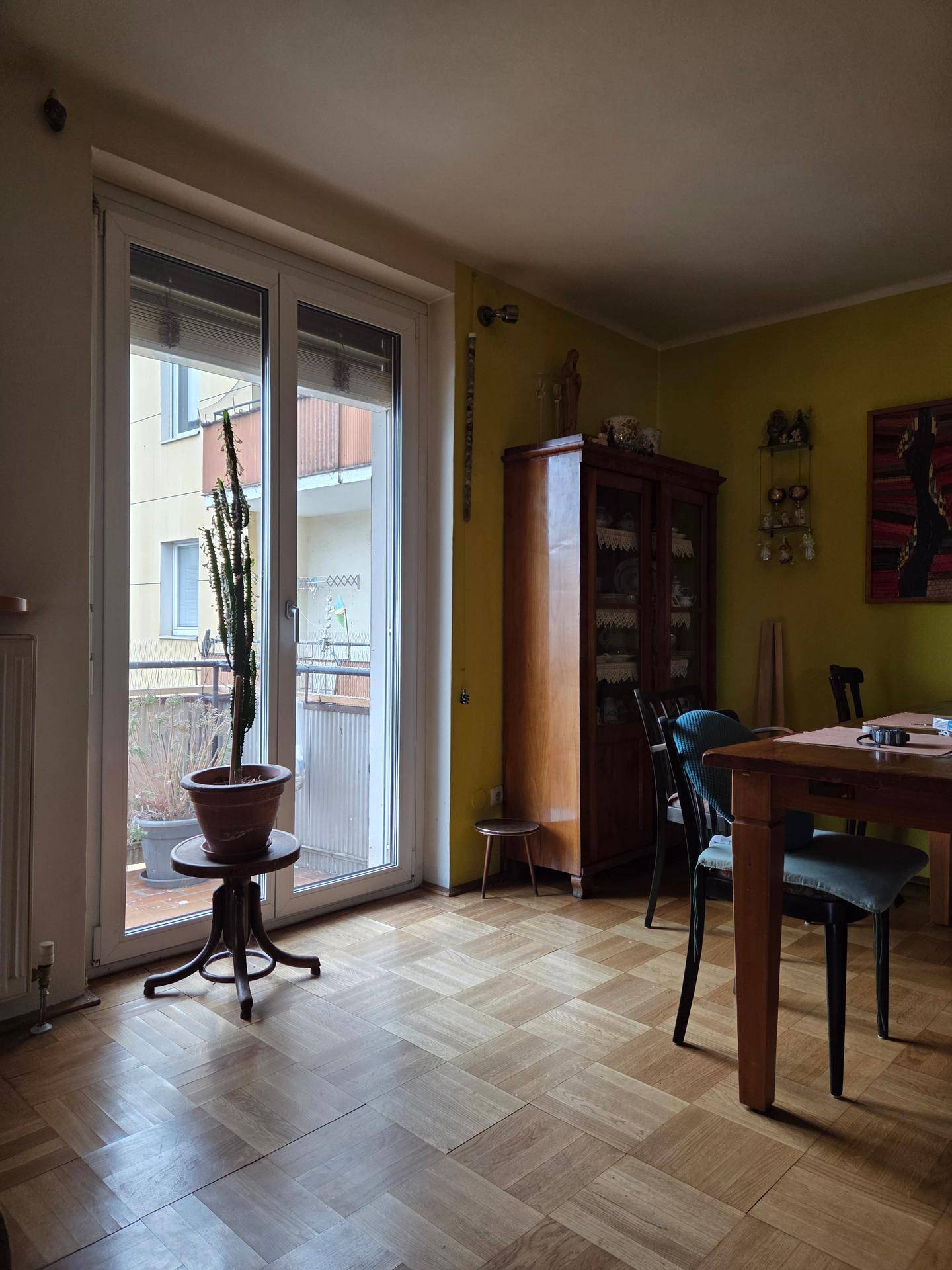 Essbereich mit Parkettboden, gelben Wänden und direktem Zugang zu einem Balkon.