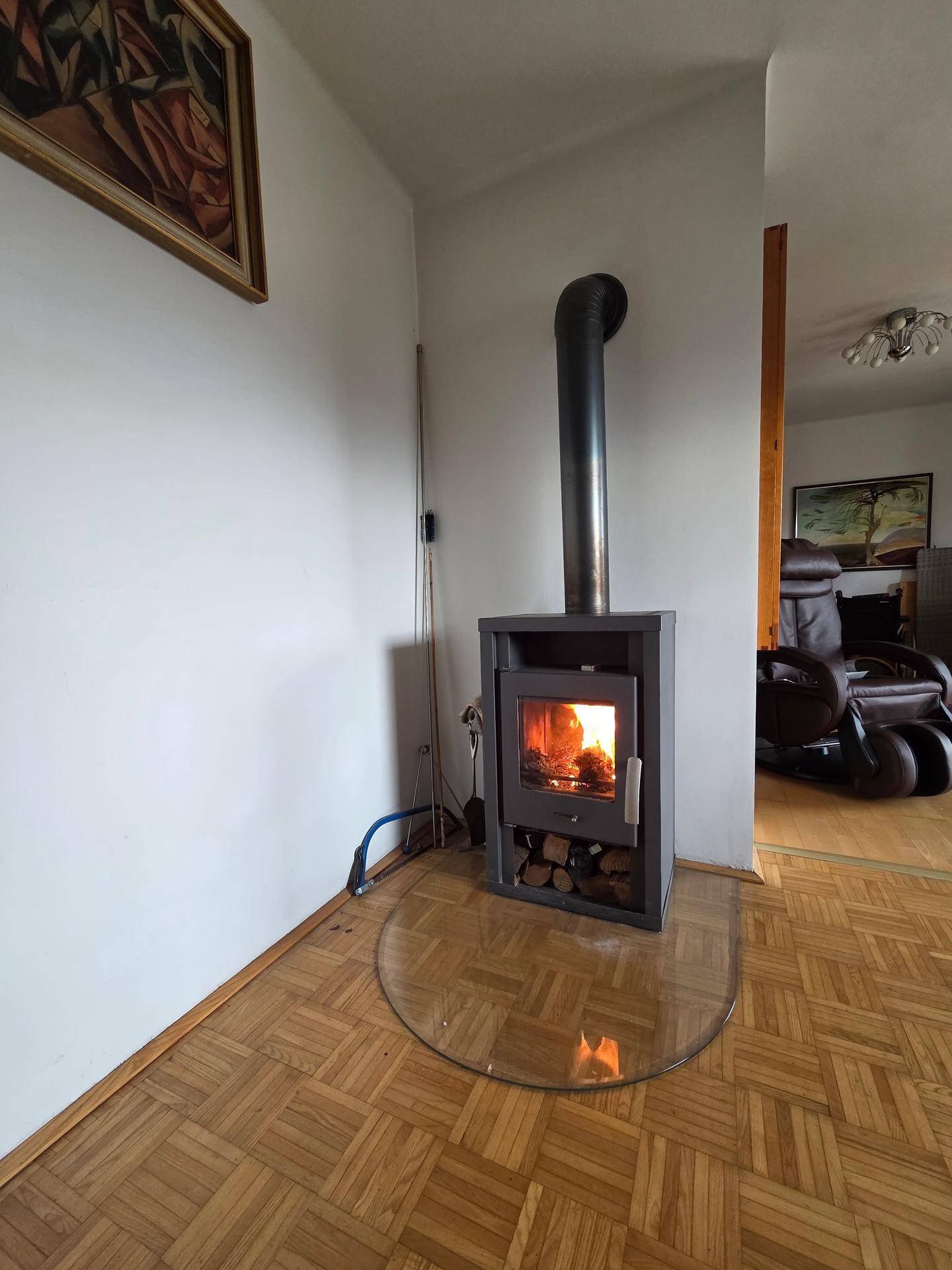 Gemütliches Wohnzimmer mit modernem Holzofen und Parkettboden für warme Abende.