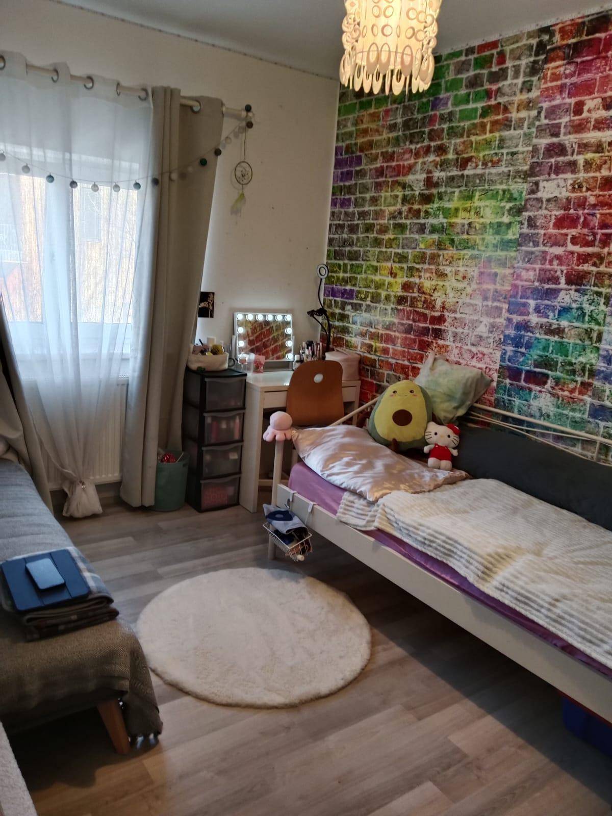 Schlafzimmer mit zwei Betten, farbiger Ziegelstein-Tapete und Fenster.