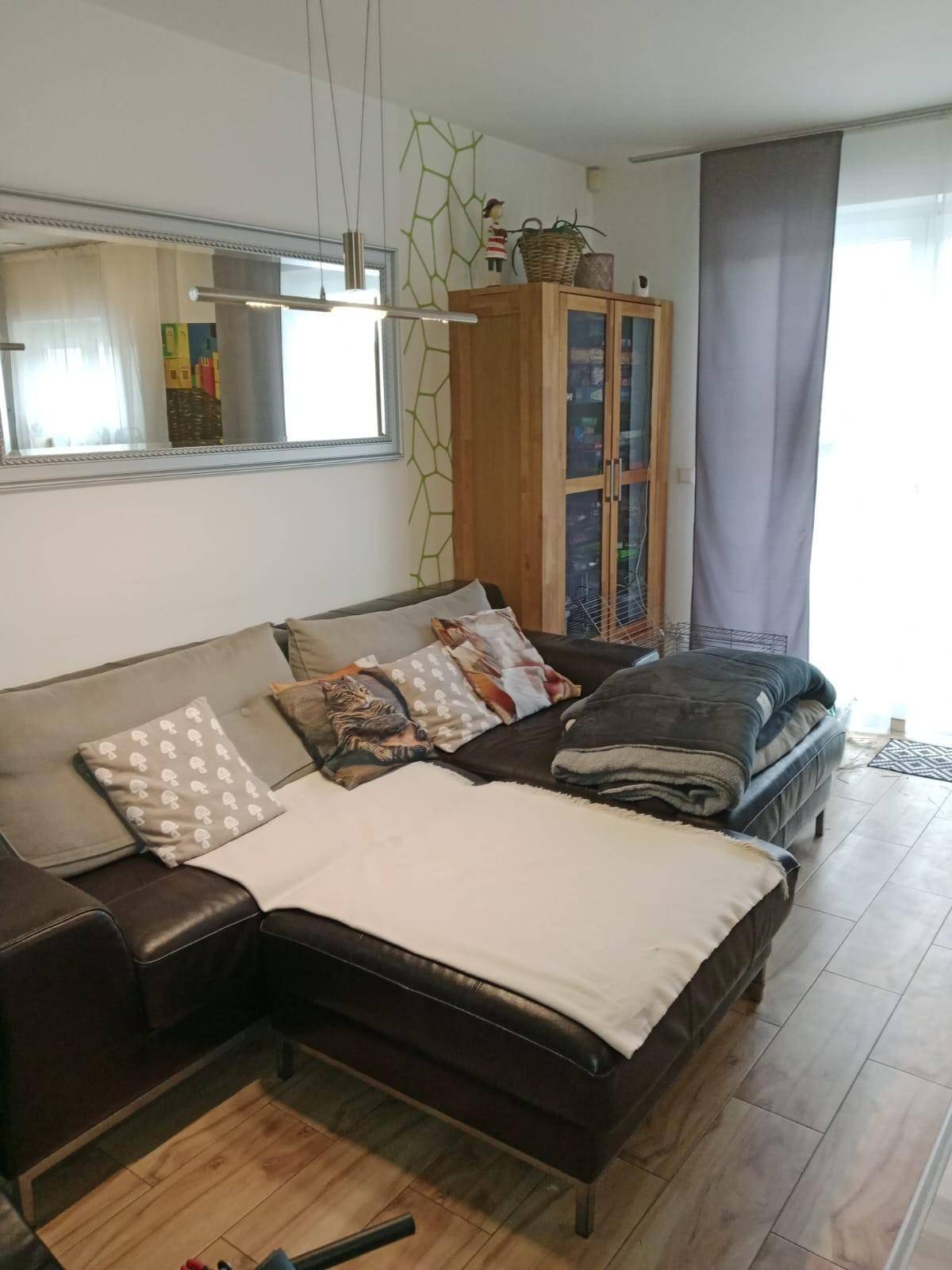 Wohnzimmer mit großem Ecksofa, Spiegel und Zugang zu einem Außenbereich.