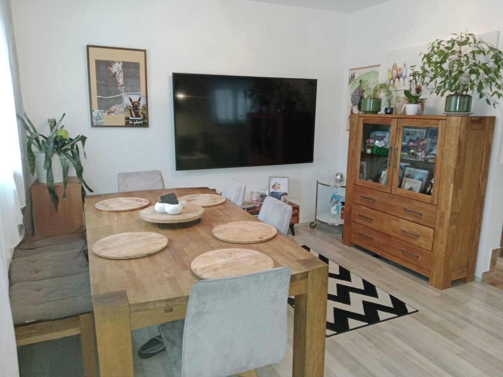 Gemütlicher Essbereich mit großem Holztisch, Stühlen und einem Holzschrank.