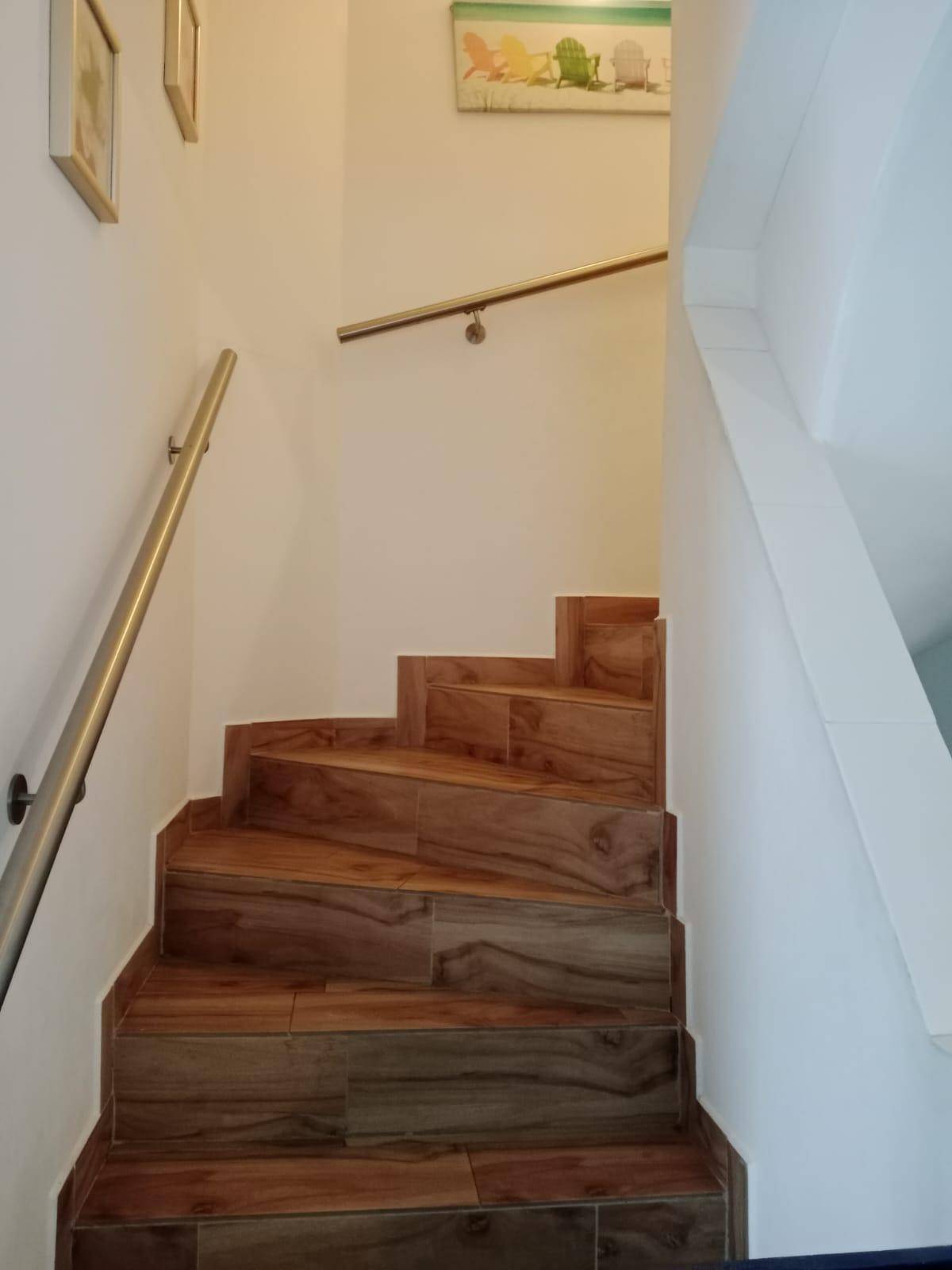 Holztreppe mit modernem Metallgeländer, die in die obere Etage führt.