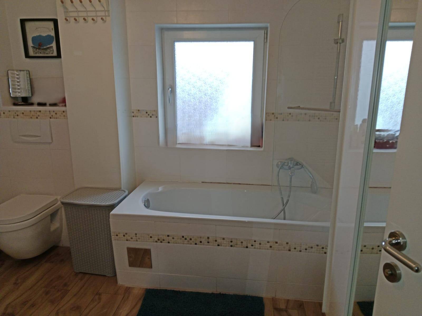 Badezimmer mit Badewanne, Toilette und einem Fenster für Tageslicht.