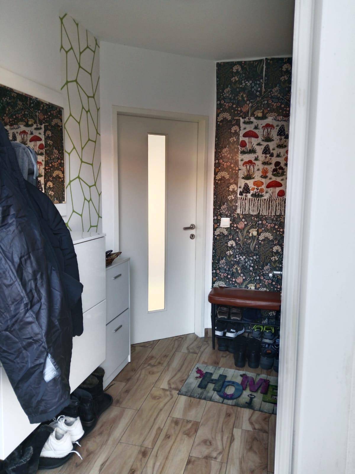 Eingangsbereich mit dekorativer Tapete, Schuhschrank und Garderobe.
