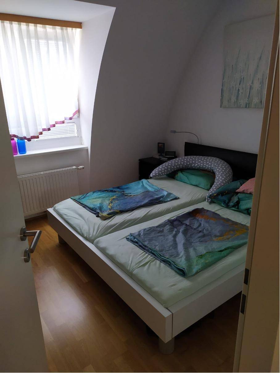 Gemütliches Schlafzimmer mit zwei Einzelbetten, Dachschräge und Fenster für natürliches Licht.