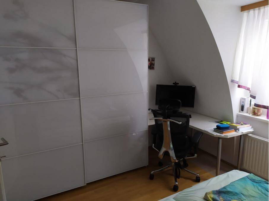 Schlafzimmer mit großem Kleiderschrank, Schreibtisch und Dachschräge, ideal für Home-Office.