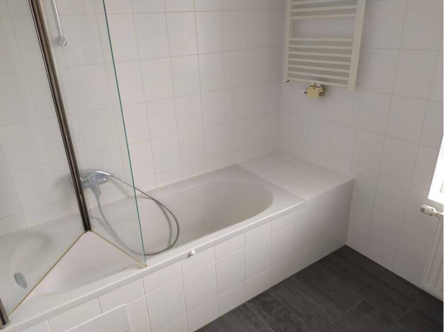 Helles Badezimmer mit Badewanne, Duschabtrennung und beheiztem Handtuchhalter.