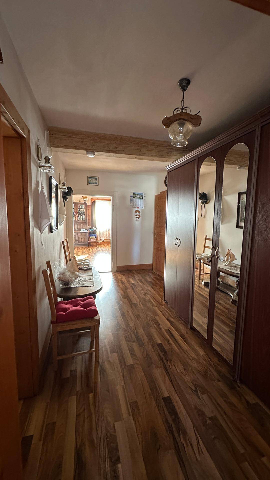 Geräumiger Flur mit Holzboden, Spiegelschrank und Blick in den Wohnbereich.