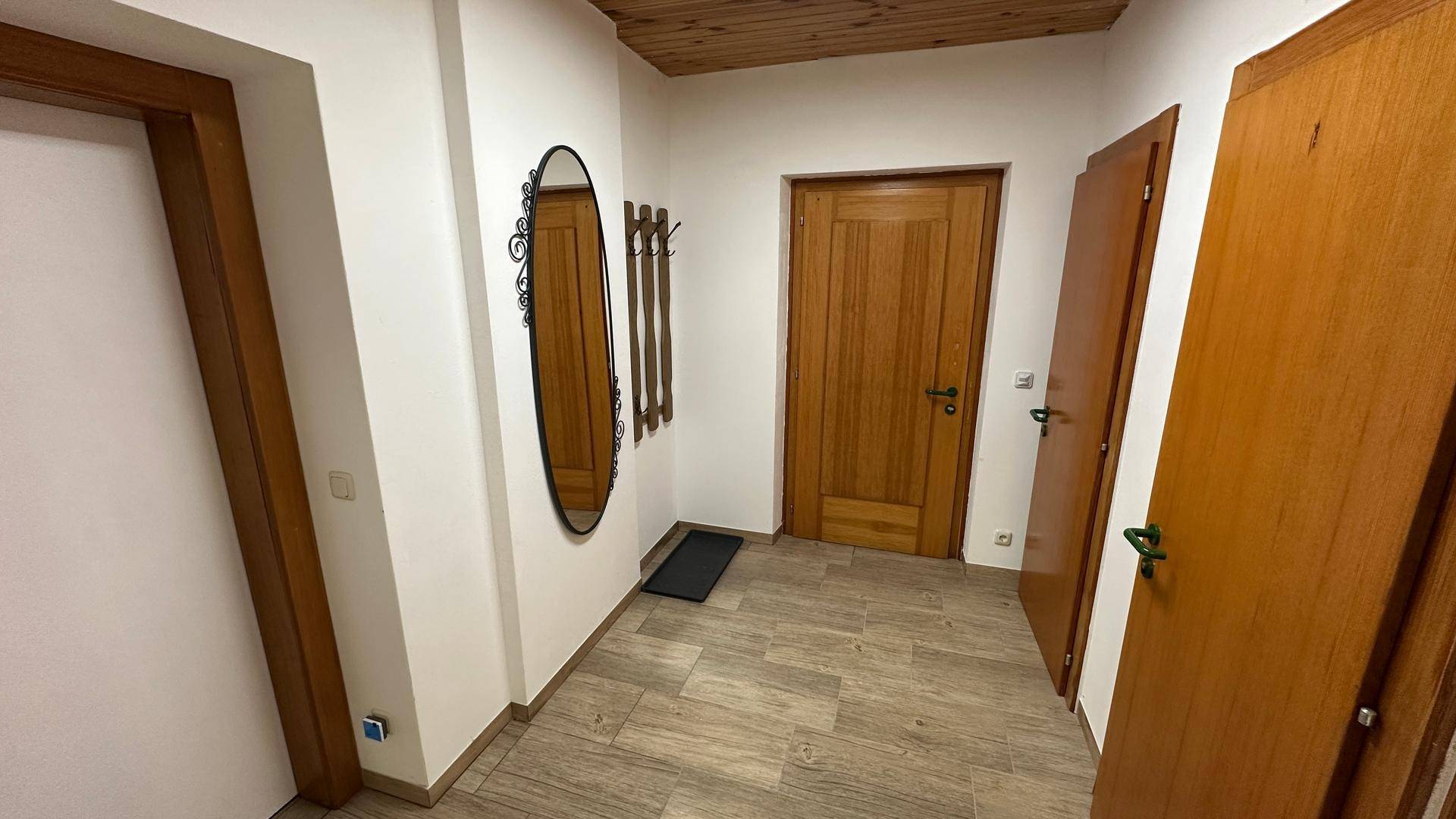 Eingangsbereich mit Holzdecke, Fliesenboden und einem dekorativen Spiegel.