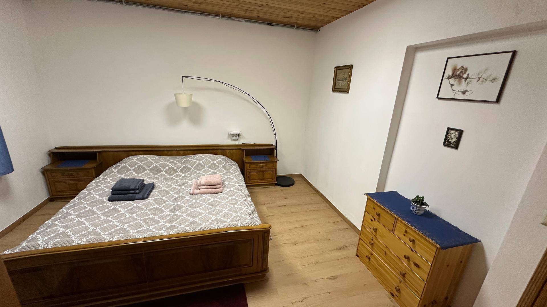 Geräumiges Schlafzimmer mit Doppelbett, Kommode und Laminatboden.