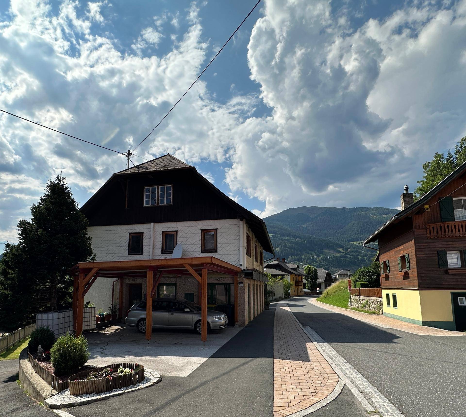 Gepflegtes Landhaus mit Holzcarport und weitem Blick auf die umliegende Berglandschaft.