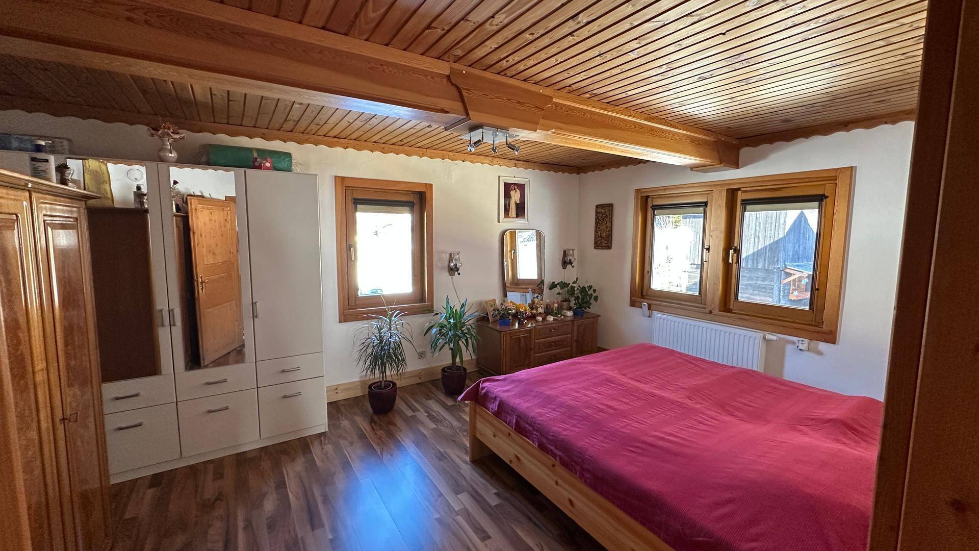 Gemütliches Schlafzimmer mit Doppelbett, Holzbalken und Einbauschränken.
