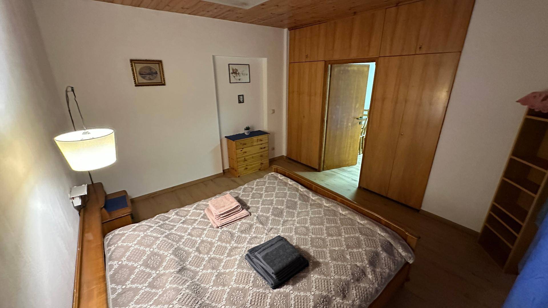 Schlafzimmer mit Doppelbett, Einbauschränken und Holzboden, gemütlich eingerichtet.