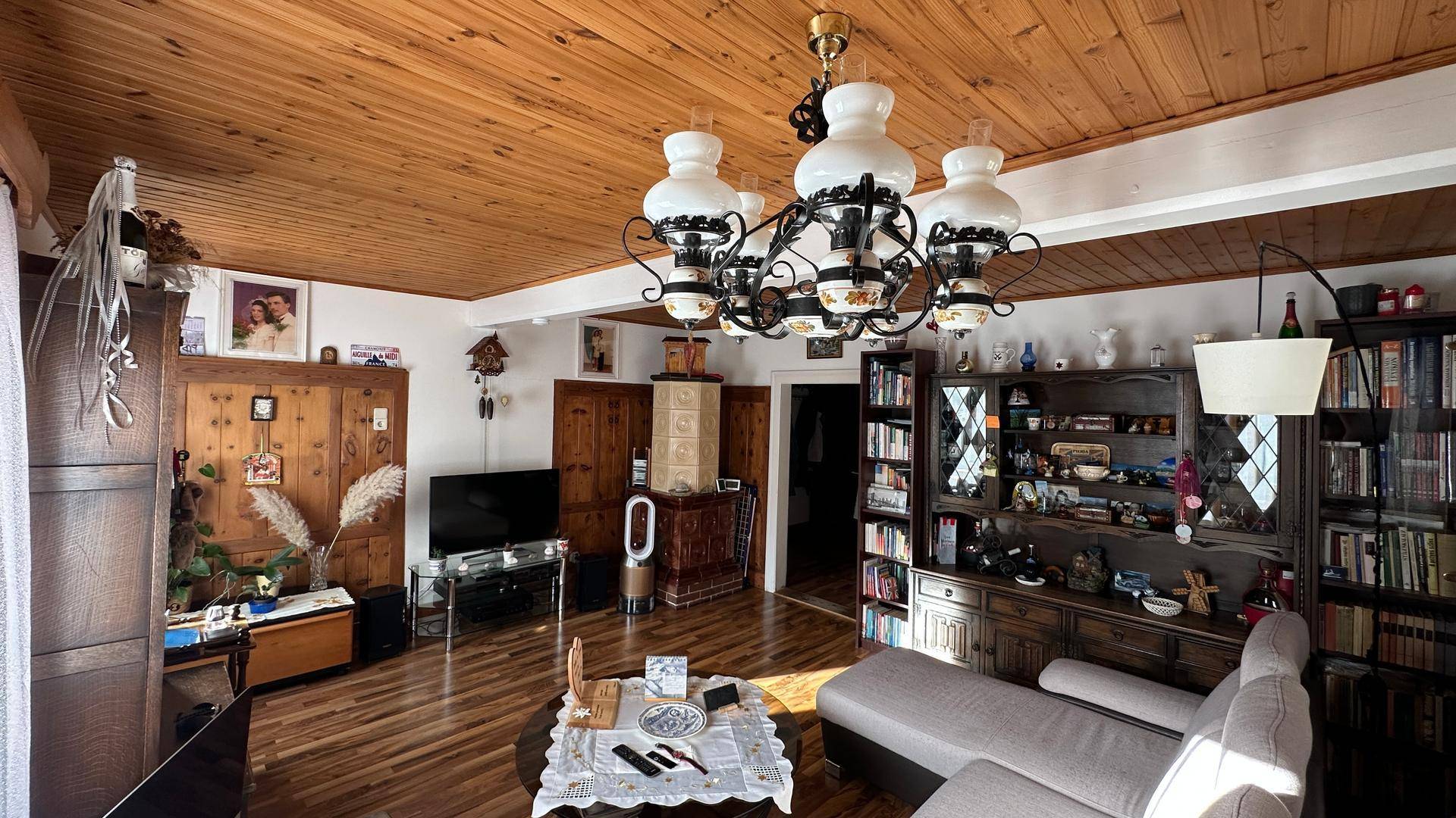 Geräumiges Wohnzimmer mit Kachelofen, Holzdecke und traditionellen Möbeln.