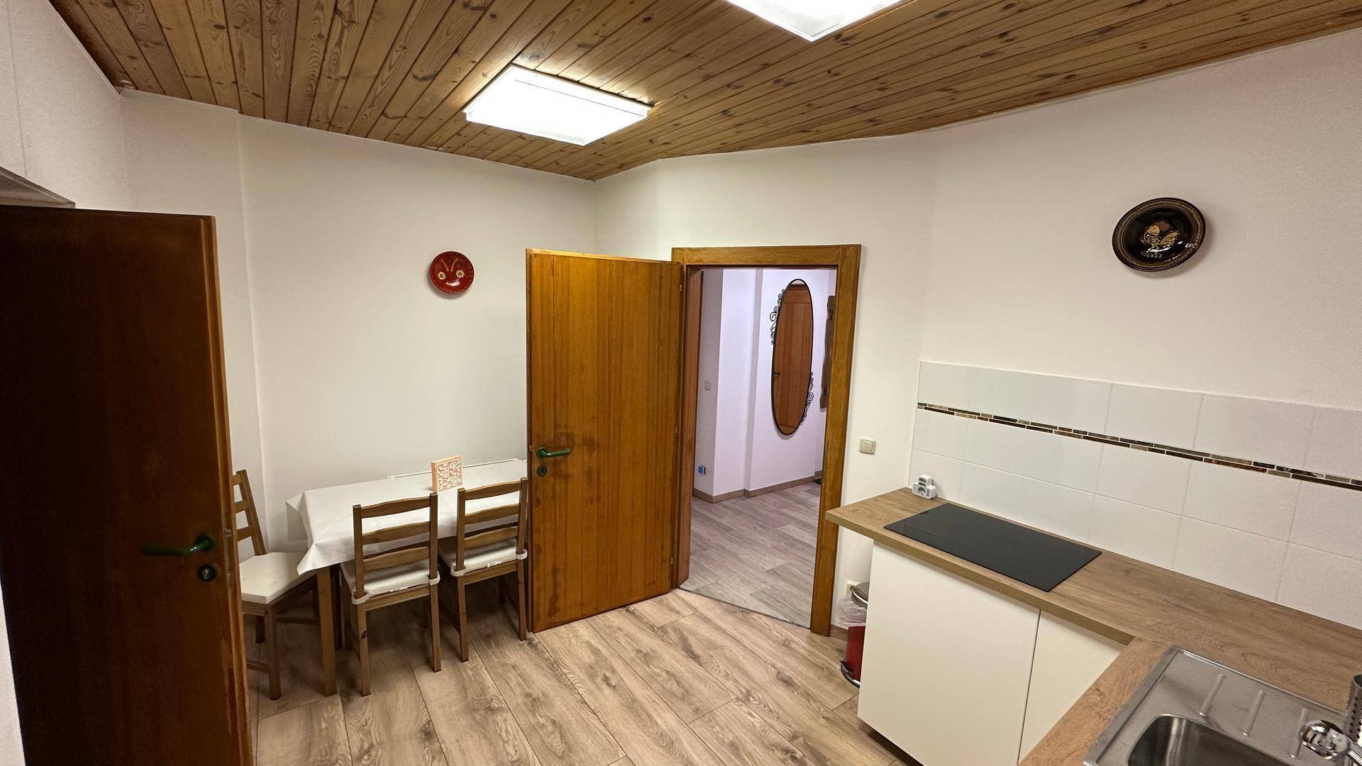 Gemütliche Küche mit Essbereich, Holzdecke und Blick in den Flur.