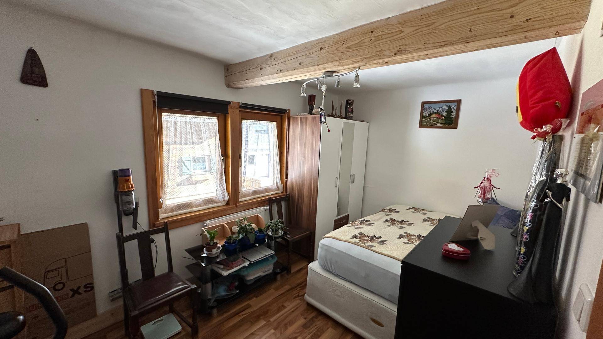 Schlafzimmer mit Einzelbett, Schreibtisch und Kleiderschrank, hell durch Fenster.