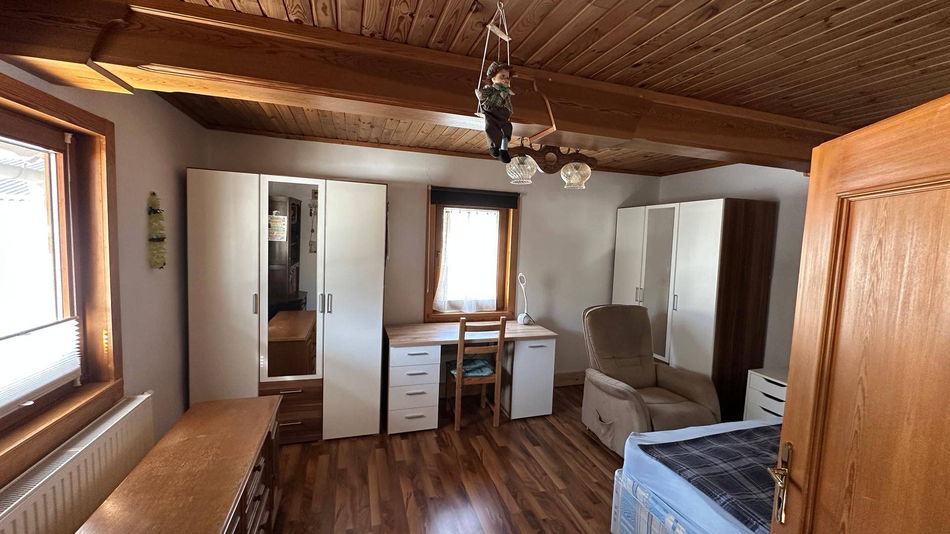 Schlafzimmer mit Schreibtisch, Kleiderschränken und Holzbalken an der Decke.