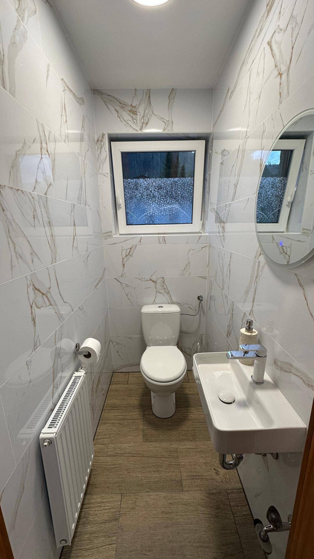 Modernes Gäste-WC mit Marmorfliesen, Fenster und wandmontierter Toilette.