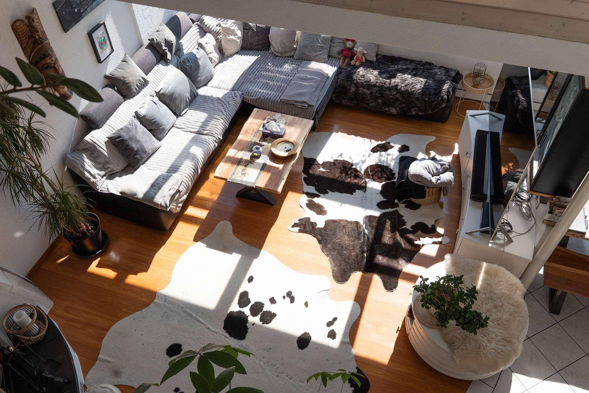 Geräumiger Wohnbereich von oben gesehen mit großer Couch und Holzboden.