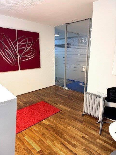 Empfangsbereich mit Holzboden, rotem Teppich und moderner Kunst an der Wand, der eine einladende Atmosphäre schafft.