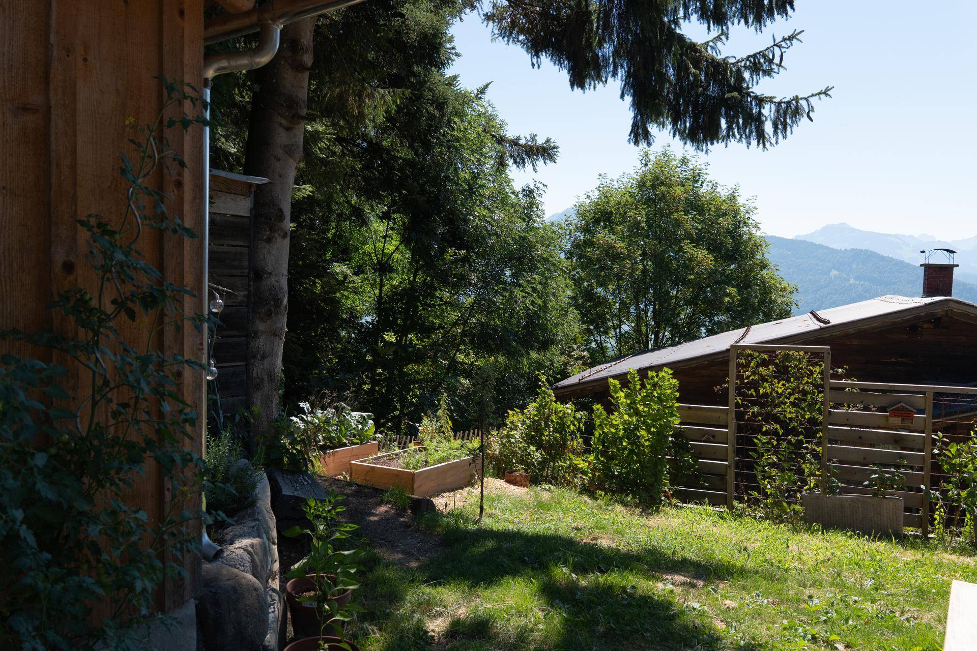 Gartenbereich mit Hochbeeten und weitem Blick auf die umliegende Berglandschaft.