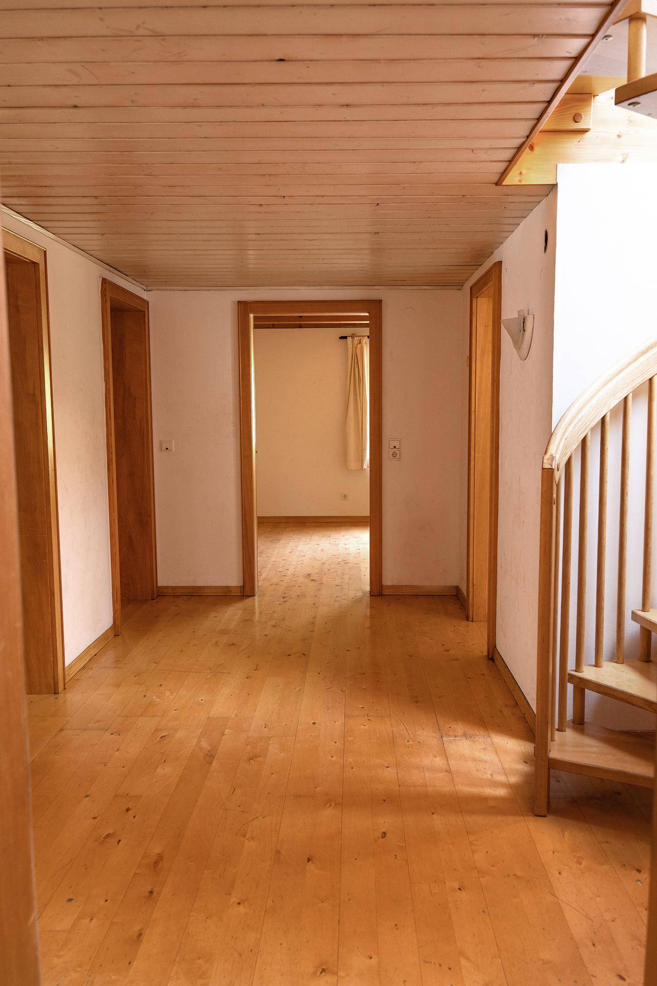 Geräumiger Flur mit hellem Holzboden, Holzdecken und einer Holztreppe, die in die oberen Stockwerke führt.