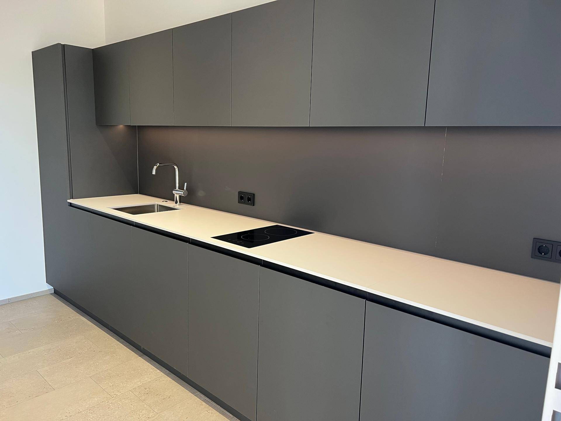 Elegante, moderne Küche in Anthrazit mit integriertem Kochfeld und minimalistischem Design, ideal für zeitgemäßes Wohnen.