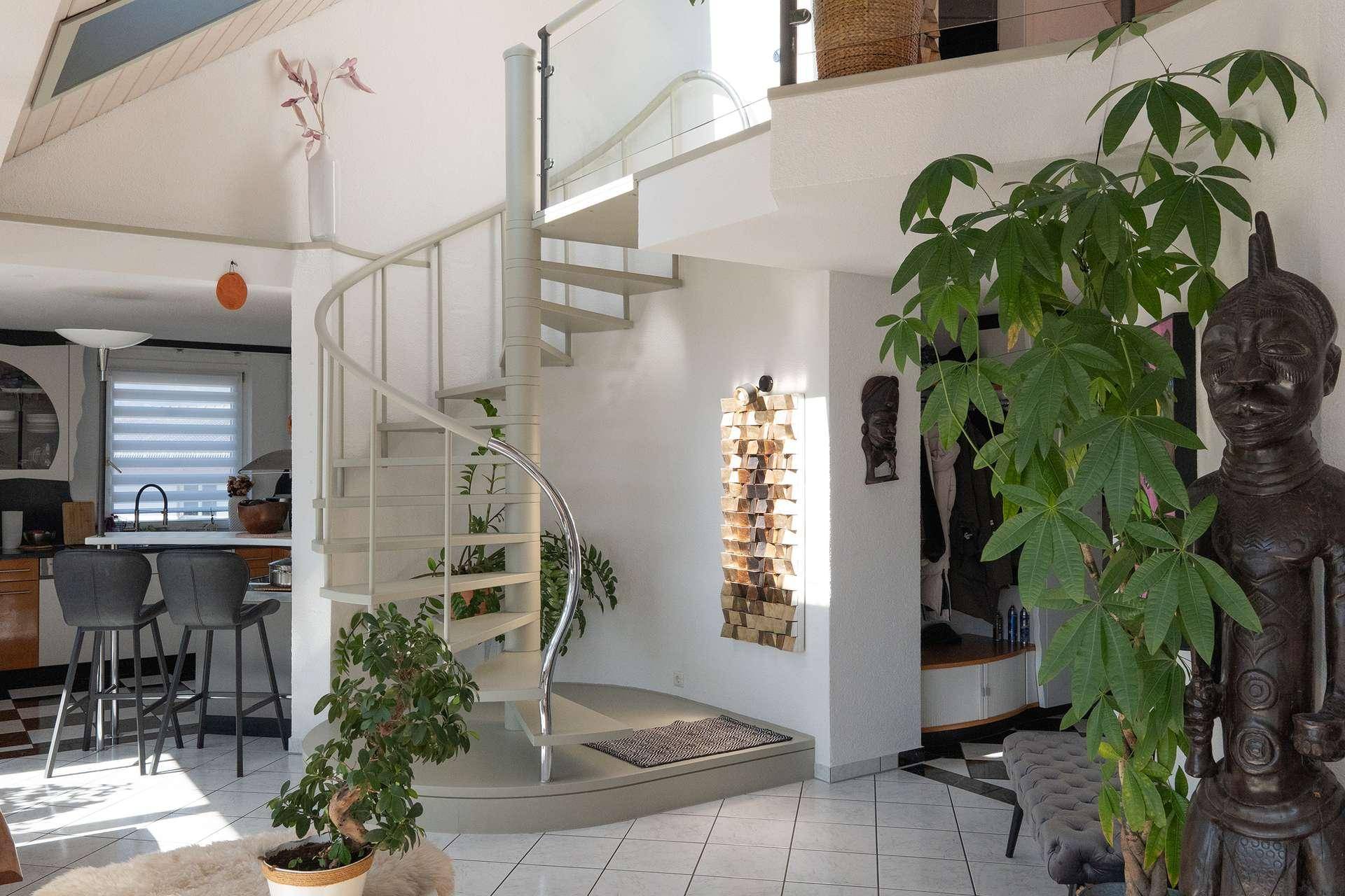 Heller Wohnbereich mit eleganter Wendeltreppe und Zugang zur Küche.