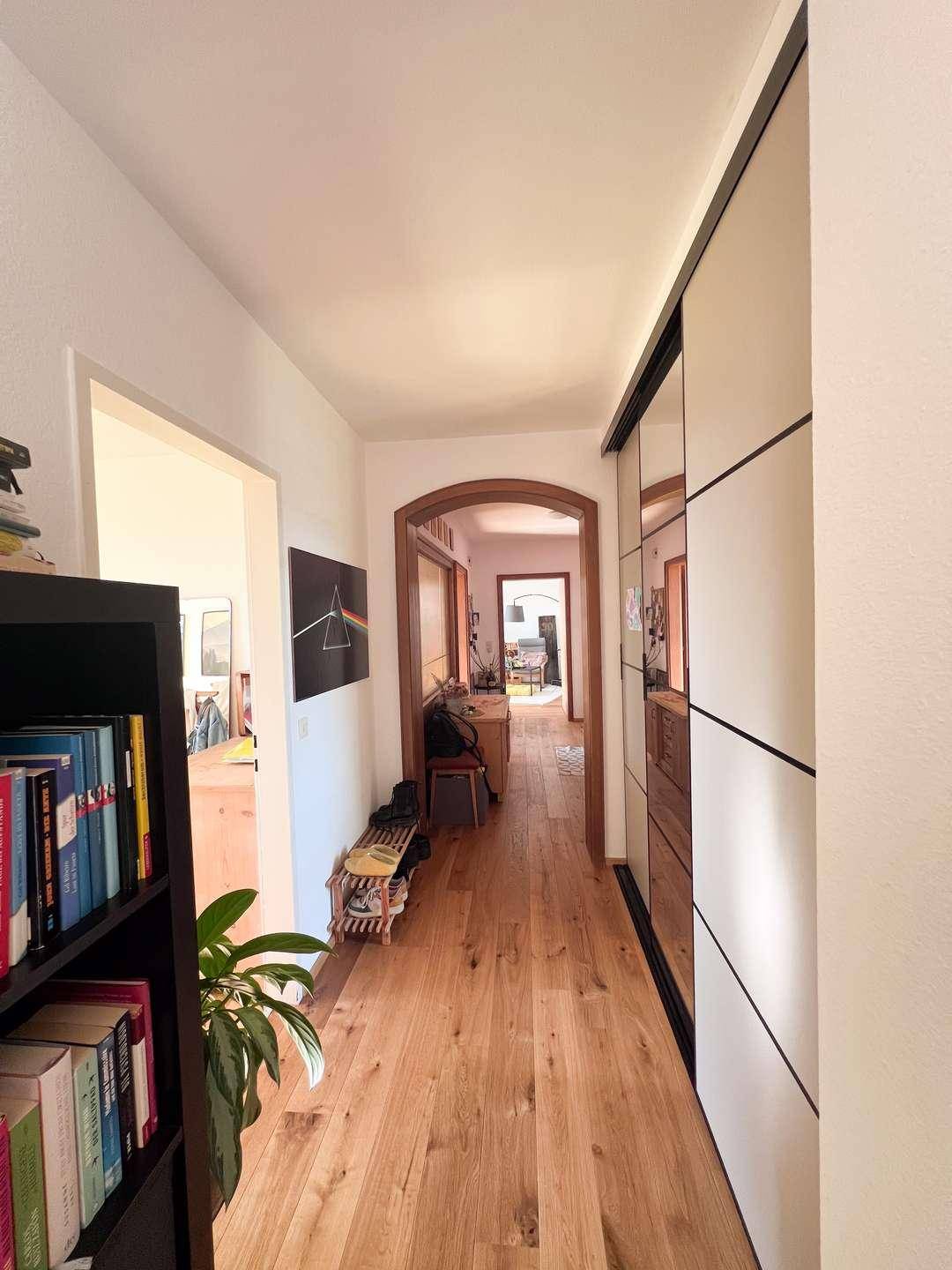 Heller Flur mit Holzboden, Spiegelschränken und Blick in weitere Räume.