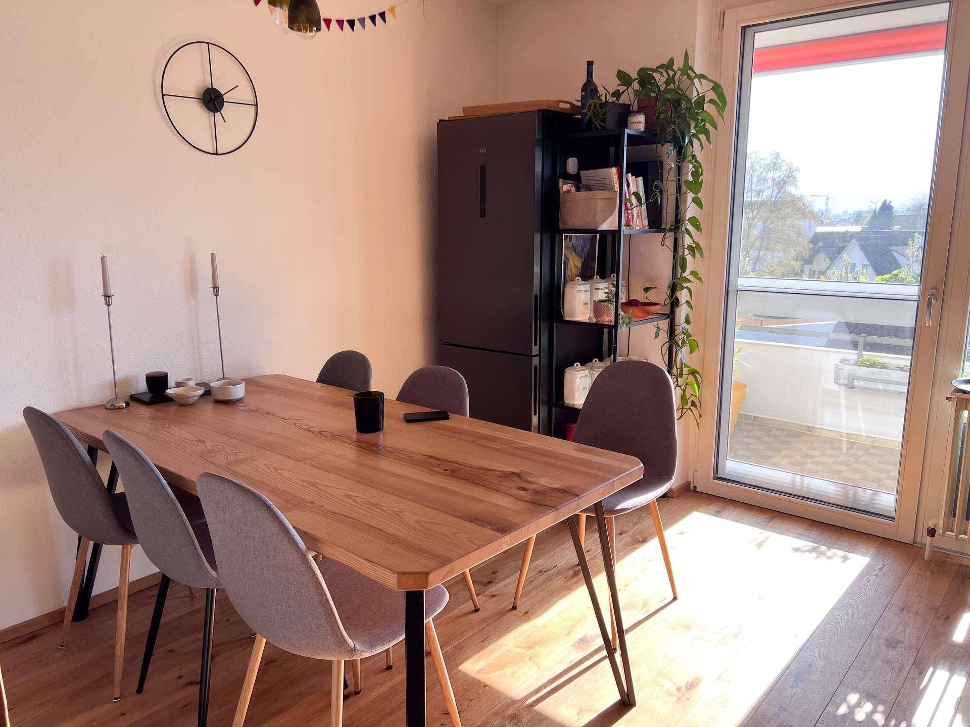 Heller Essbereich mit Holztisch, modernen Stühlen und Zugang zu einem Balkon.