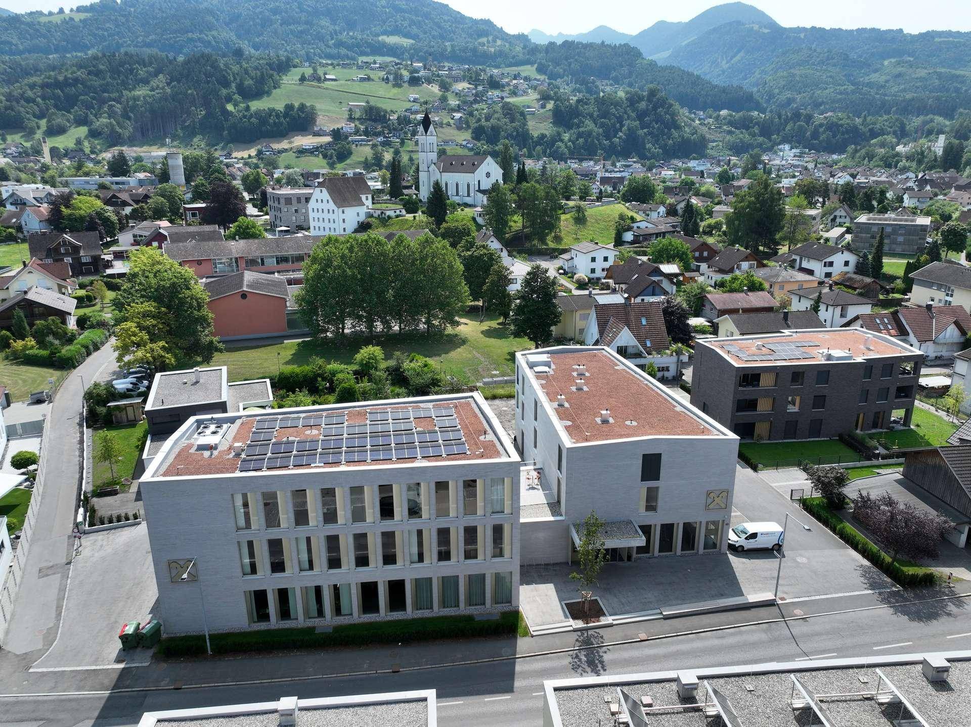 Luftaufnahme eines modernen Gebäudekomplexes mit Solaranlage auf dem Dach in ländlicher Umgebung.