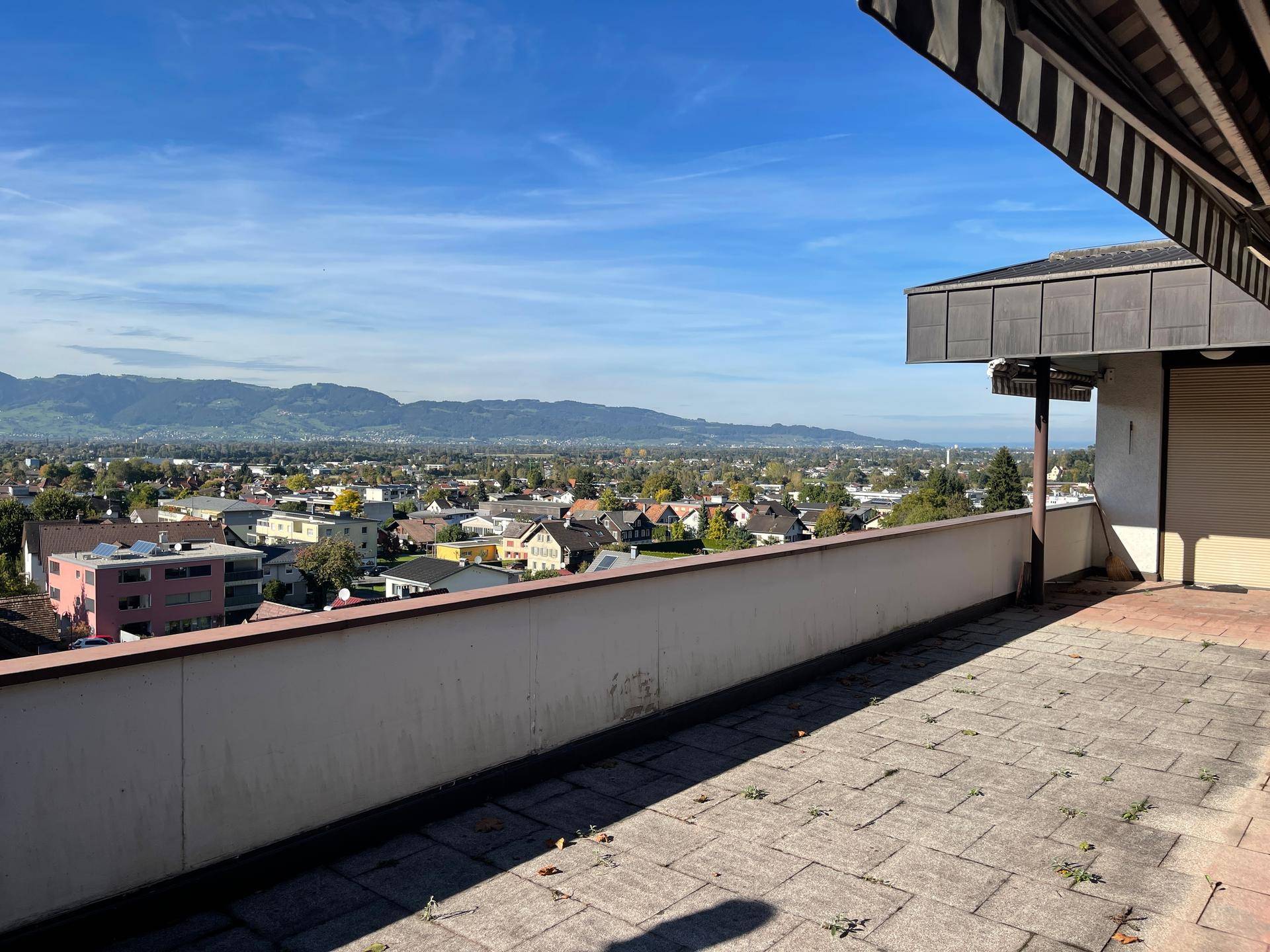 Große geflieste Terrasse mit weitem Blick über die Stadt und die umliegende Berglandschaft.