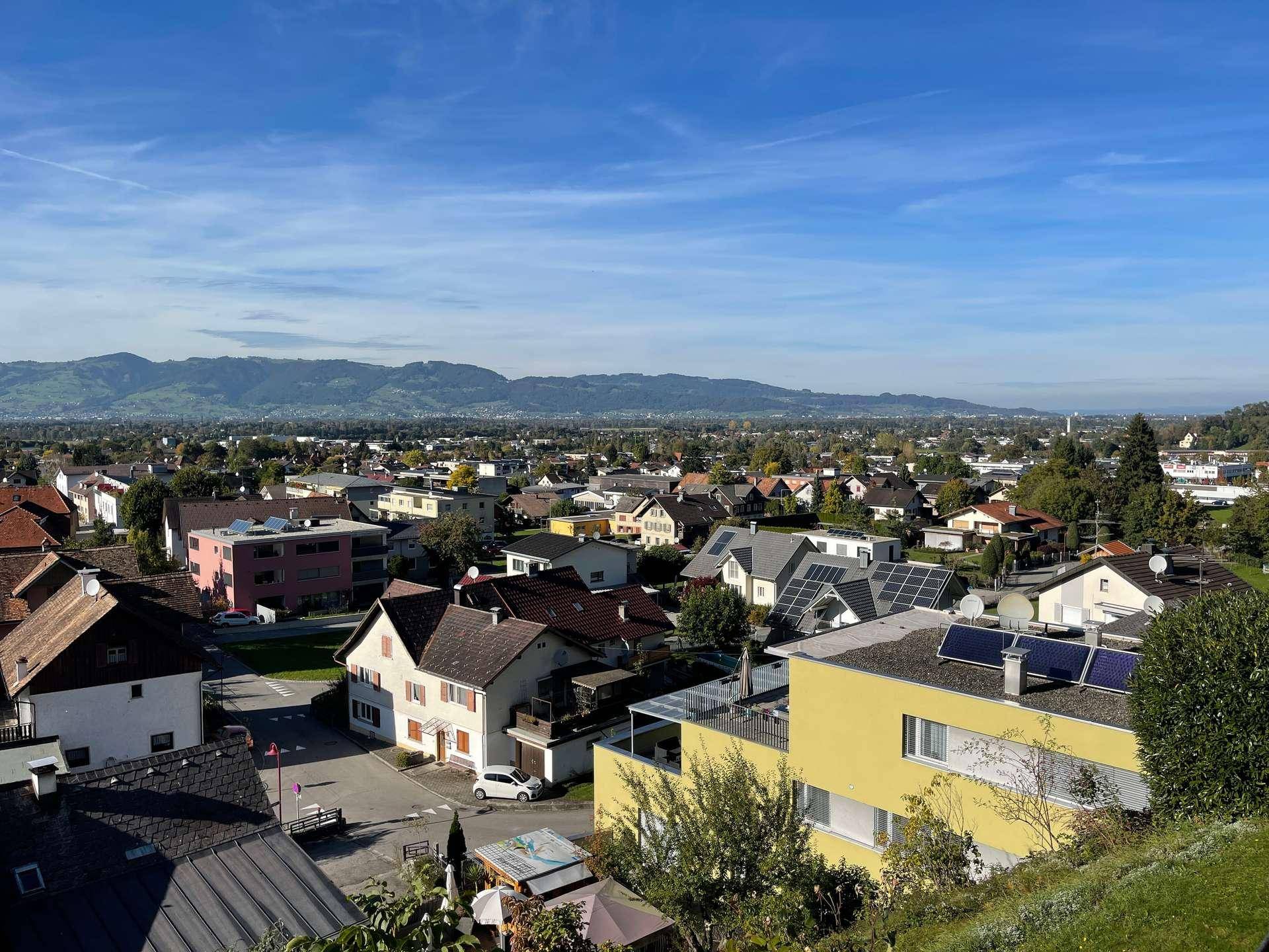 Weitblick über eine Siedlung mit vielen Häusern und Bergen im Hintergrund.