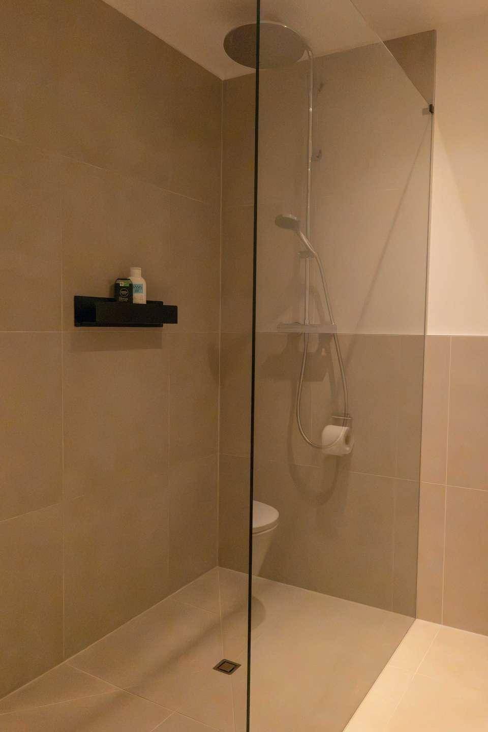 Geräumige begehbare Dusche mit Regenduschkopf und modernen Fliesen.