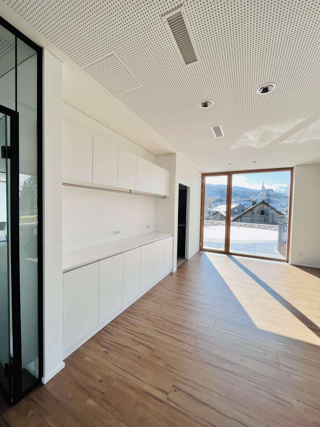 Moderne Küchenzeile mit weißen Schränken, viel Stauraum und Zugang zu einem Balkon mit Aussicht.