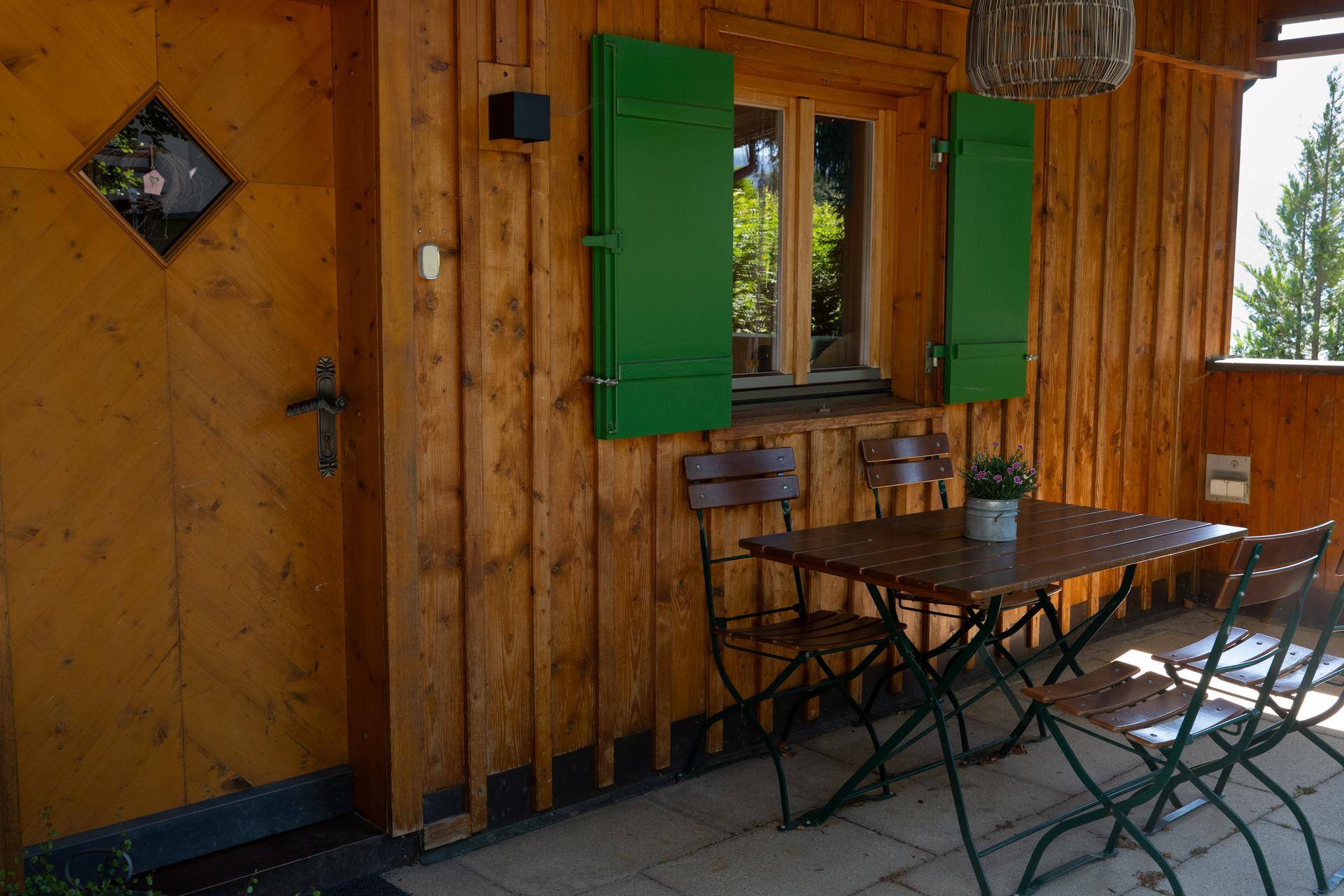 Gemütlicher Essbereich im Freien auf der Terrasse mit Holztisch und Stühlen vor der Holzfassade.