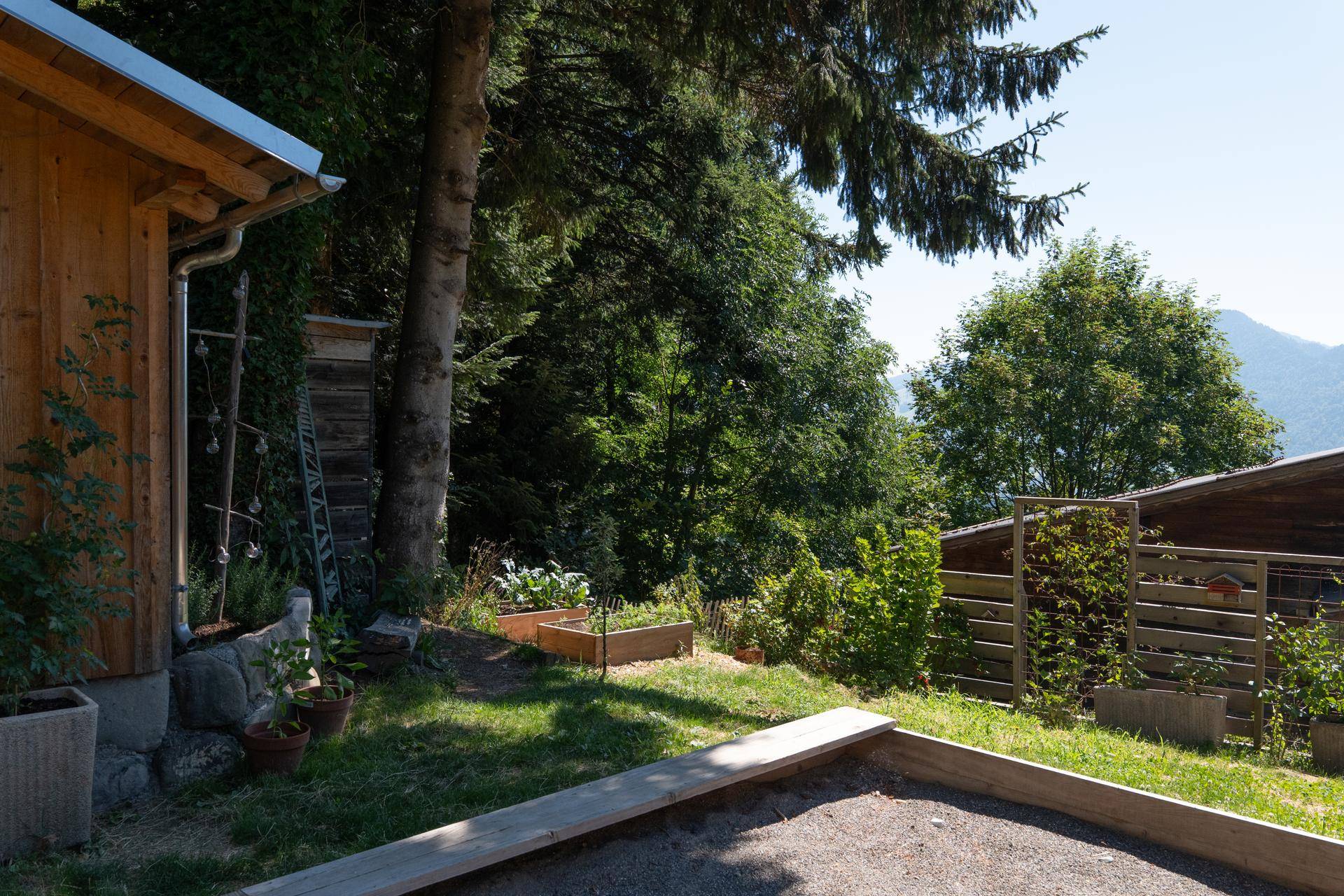 Sonnige Gartenecke mit Hochbeeten und weitem Blick auf die umliegende Berglandschaft.