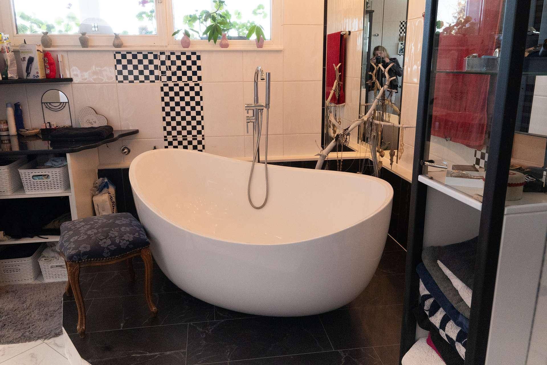 Modernes Badezimmer mit freistehender Badewanne und schwarz-weißen Fliesen.