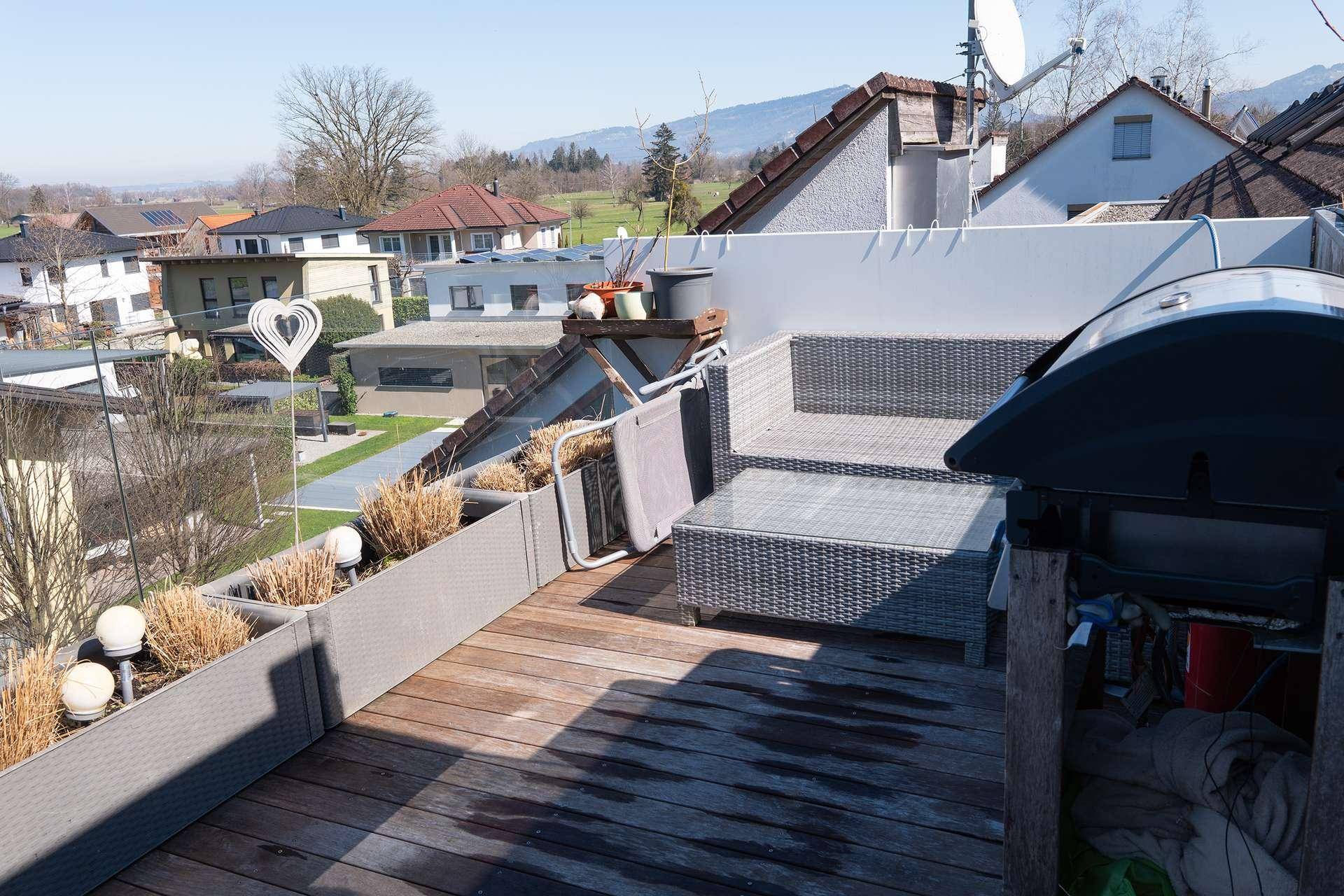 Geräumige Dachterrasse mit Holzbelag, Sitzgelegenheiten und Grillbereich.