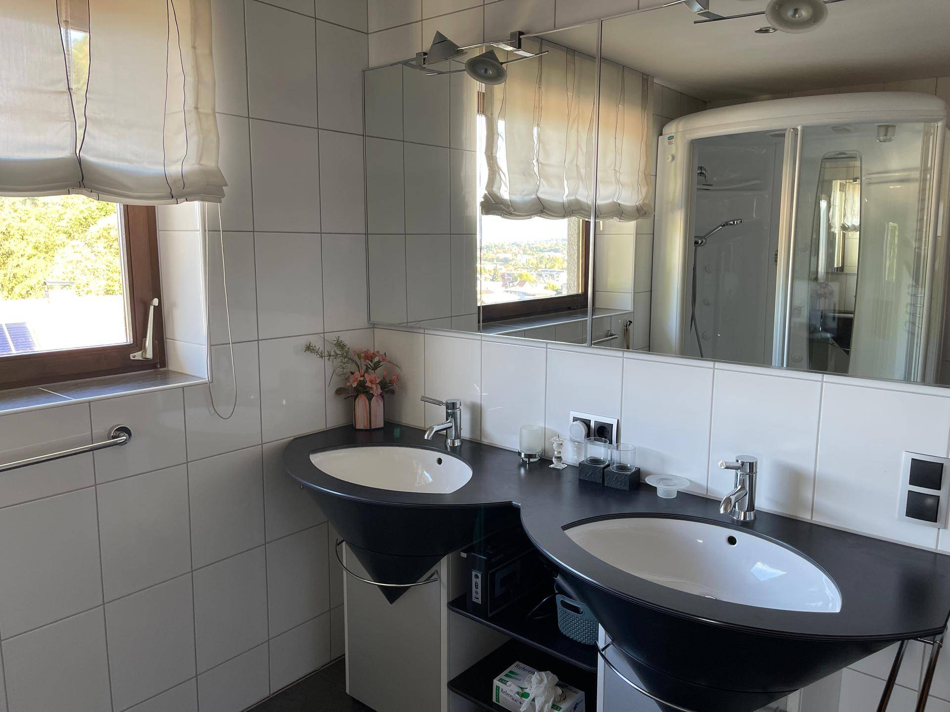 Detailansicht des Doppelwaschbeckens im Badezimmer mit großem Spiegelschrank und Fliesen.