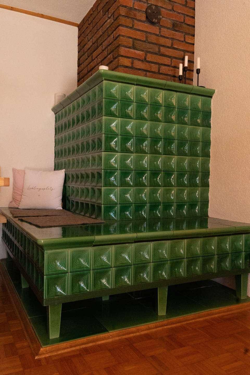 Traditioneller grüner Kachelofen mit Sitzbank, der Wärme und Gemütlichkeit spendet.