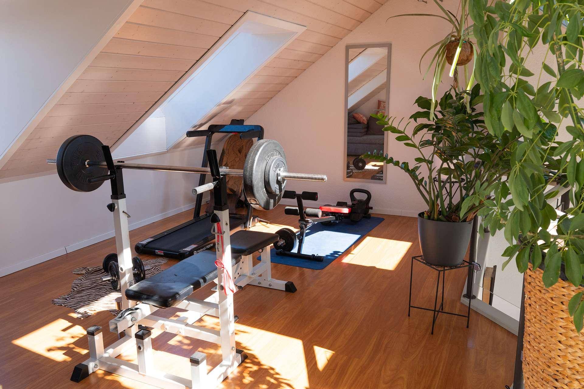 Fitnessraum im Dachgeschoss mit Trainingsgeräten und Holzboden.