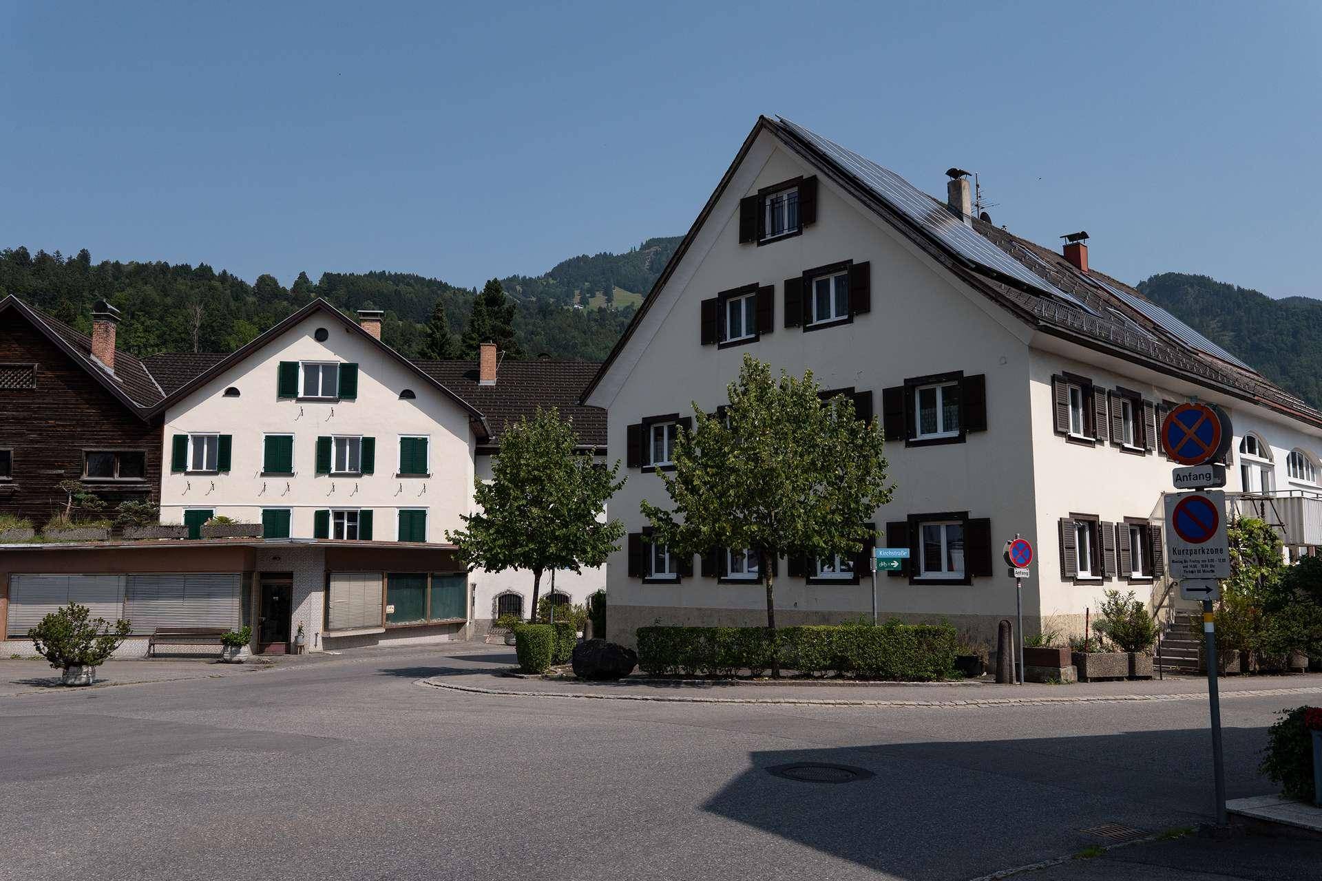 Eine Reihe von traditionellen Gebäuden mit Satteldächern und grünen Fensterläden in einer ländlichen Umgebung.